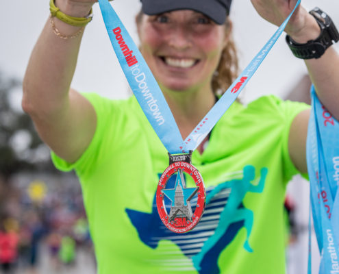 3M Half Marathon Volunteer handing out a finisher medal