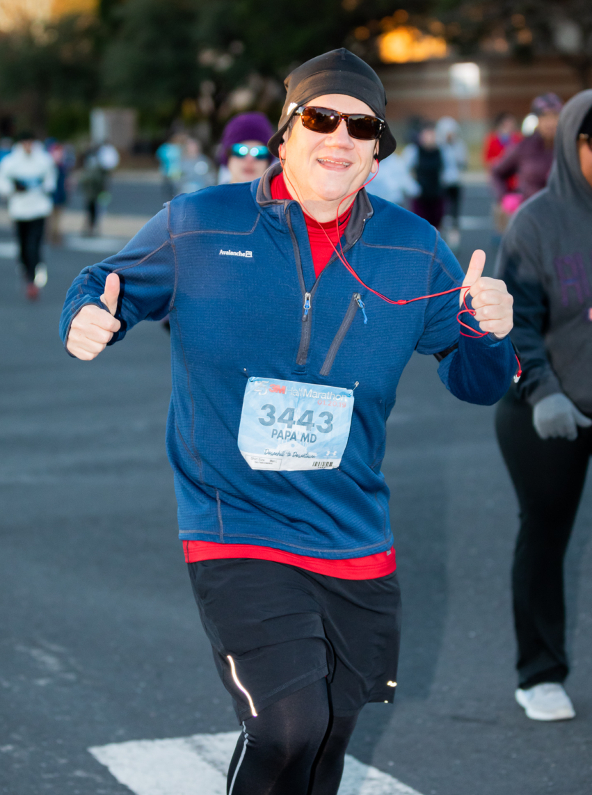Runner gives two thumbs up during 2019 3M Half Marathon while listening to music. Runners can make their own playlist to help them get up in the morning for their morning run.