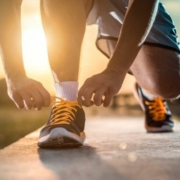 Image of runner tying their shoes as the sun rises. Use our blog's holiday training tips to stay on track for 3M Half Marathon.
