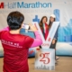 A 3M Half Marathon Ambassador takes a photo of two runners and the oversized 2019 3M Half Marathon medal at the 2019 3M Half Marathon expo. Take your photo with a giant 2020 3M Half Marathon medal, one of the many 2020 expo highlights.