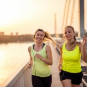 Image of female runners listening to their running playlist while on a run. This 3M Half Marathon blog showcases 10 new songs for a running playlist update.