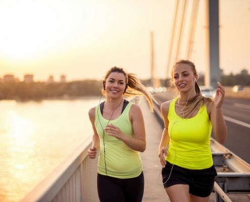 Image of female runners listening to their running playlist while on a run. This 3M Half Marathon blog showcases 10 new songs for a running playlist update.
