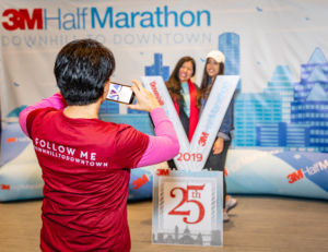 Image of a 3M Half Marathon Ambassador taking a photo of two runners at the 2019 3M Half Marathon expo. This blog has everything you need to get ready for the 2020 3M Half Marathon!