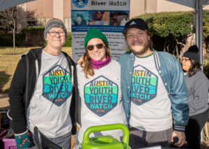 Image of 3 Austin Youth River Watch representatives at their booth at the 2019 3M Half Marathon. 3Mgives selected Austin Youth River watch as the beneficiary of the 26th annual 3M Half Marathon on January 19, 2020.