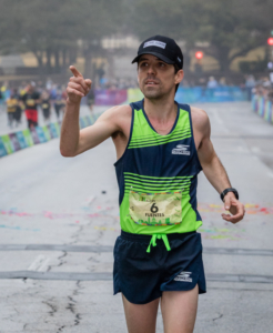 Image of David Fuentes crossing the 2018 Austin Marathon finish line in 4th place. He is running in the 26th annual 3M Half Marathon's elite field.