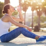 Image of woman drinking from a water bottle after a run. Proper hydration is an important self-care tip in this 3M Half Marathon blog.