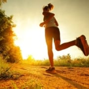 Image of a woman running on a trail. They're following the 3M Half Marathon's summertime running advice to beat the heat while they run.