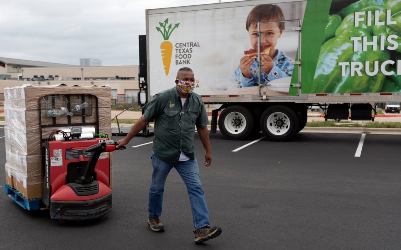 An employee of the Central Texas Food Bank, the 2021 beneficiary of the 3M Half Marathon, pulls a pallet jack full of food after unloading a truck.