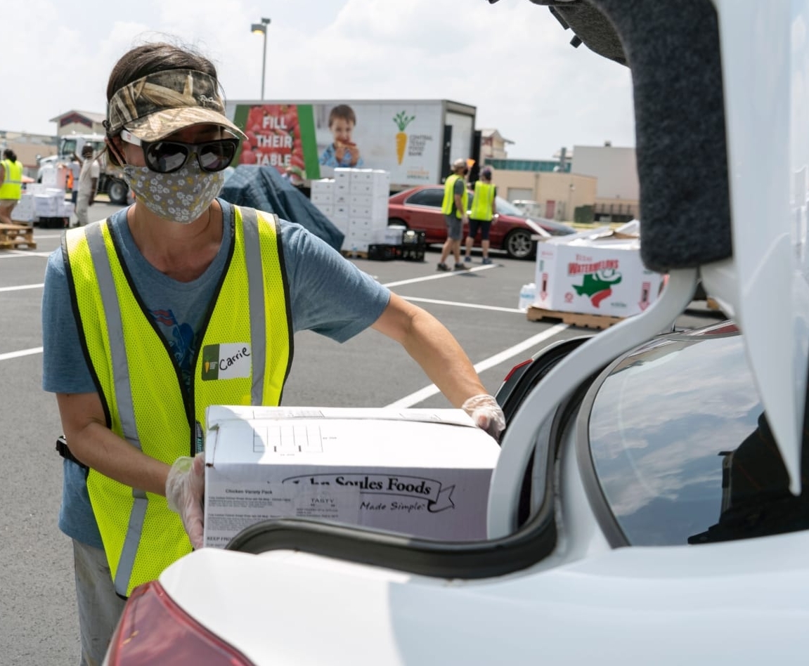 An employee of the Central Texas Food Bank, the 2021 beneficiary of the 3M Half Marathon, loads a box into the trunk of a car.