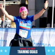 Female runner crosses the 3M Half Marathon with her arms raised triumphantly in the air. Text on design reads How to Set Training Goals. Learn more at https://downhilltodowntown.com/set-training-goals/